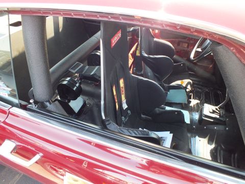 2003 Ford Crown Victoria - roll-caged interior of a maroon race car shows black racing seats and harnesses viewed through the side window.