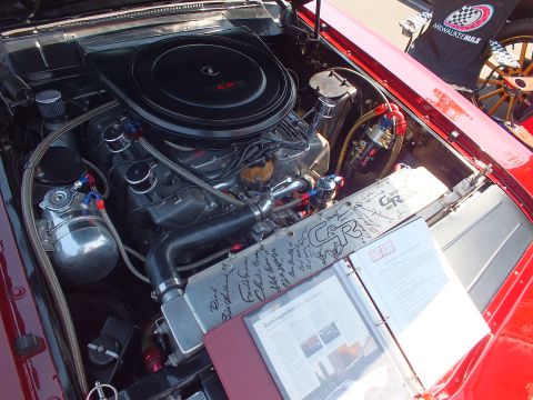 2003 Ford Crown Victoria - vintage V8 engine bay shows a large black round air cleaner and braided fittings, with a signed binder resting on the fender.