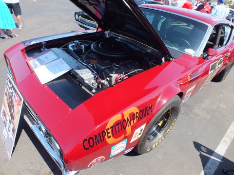 2003 Ford Crown Victoria - dark red race car marked Competition Proven and number 23 sits with hood raised on Goodyear tires at an outdoor show.