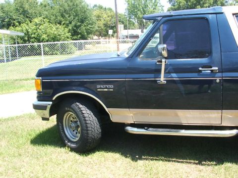 1991 Ford Bronco - Side view of a Ford Bronco with a two-tone paint scheme and chrome running boards.