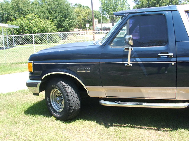 Dark blue and tan Ford Bronco side view, showing front fender, door, and running board
