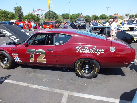 2003 Ford Crown Victoria - maroon Ford Talladega fastback race car numbered 72 sits at an outdoor show beside a 429 cubic inch display banner.