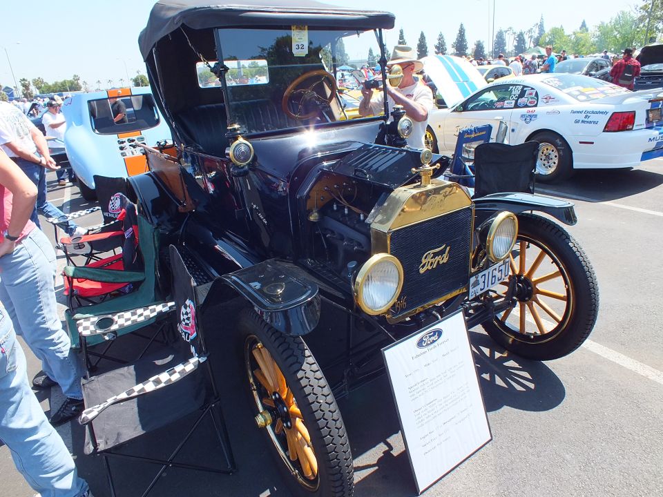 Black antique Ford Model T roadster with brass radiator and spoked wheels at show