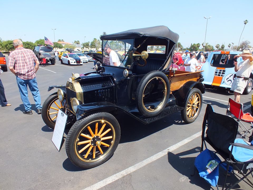 Black antique Ford with brass trim, folding top and yellow wooden-spoke wheels at show