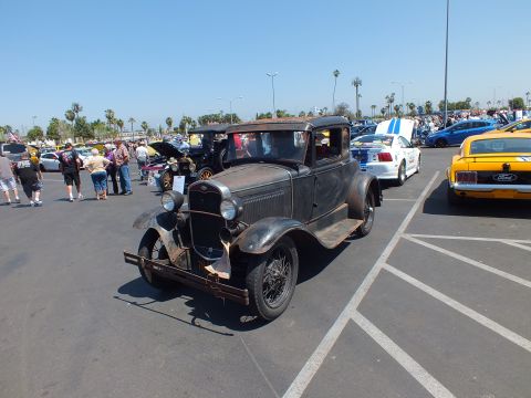 Weathered antique black Ford coupe with patina parked in lot, front quarter view