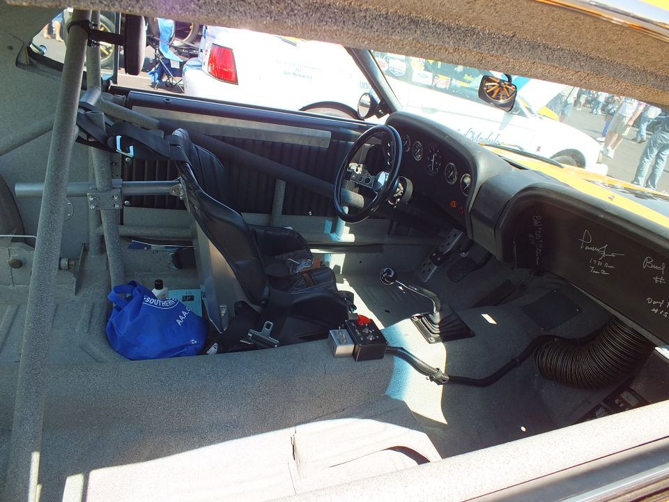 Stripped race car cockpit with roll cage, single seat and signed dashboard