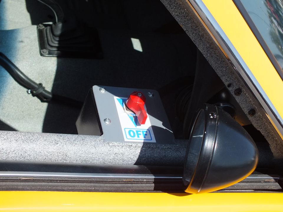 Close-up of red master battery cutoff switch labeled OFF on yellow race car