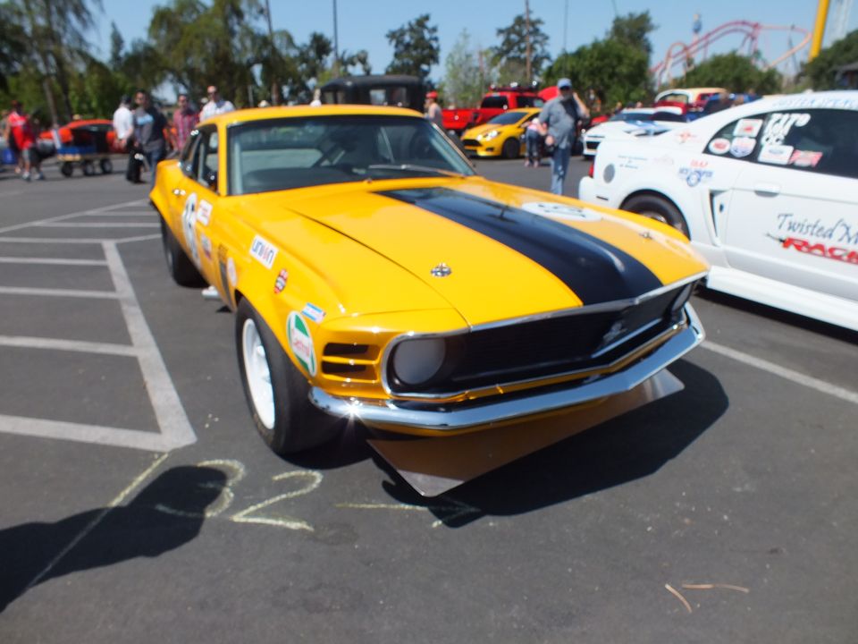 Yellow Ford Mustang race car with black stripe, front quarter view at car show