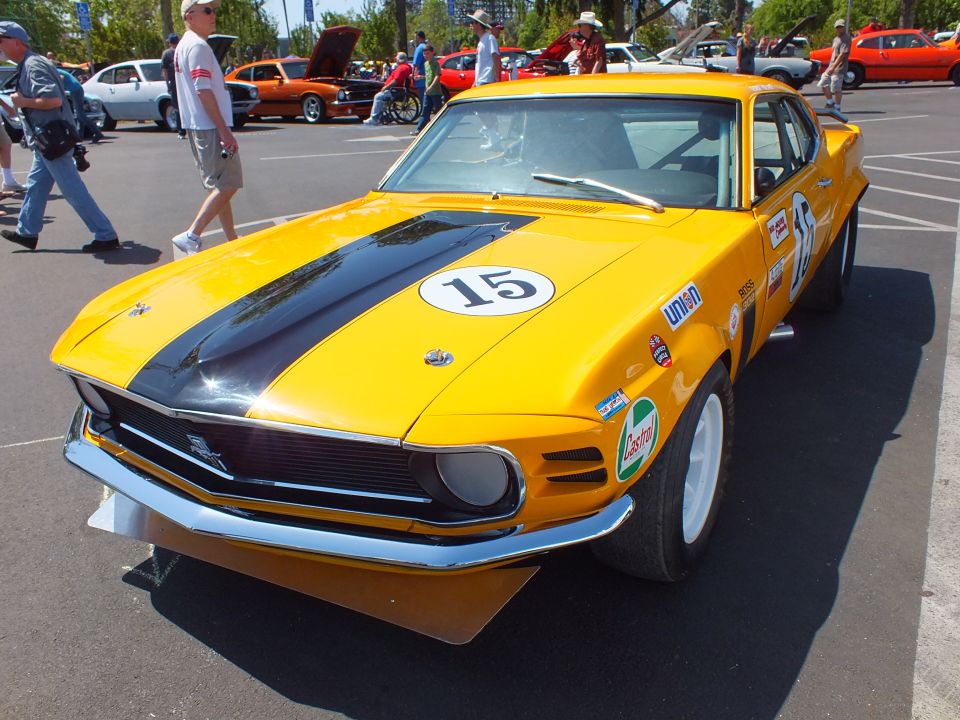 Yellow Ford Mustang race car #15 with black stripe, low front three-quarter view