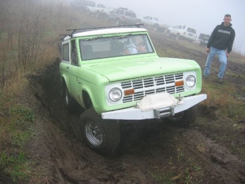 1989 Ford Bronco - A green 1978 Ford Bronco navigates a muddy incline, with other vehicles visible in the background.