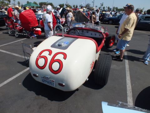 White vintage roadster racer numbered 66 at car show
