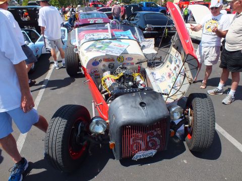 Red and white hot rod with sticker-covered hood, exposed engine