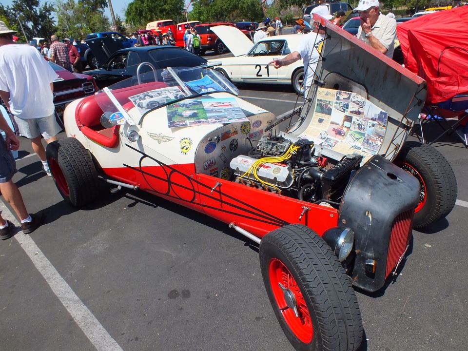 Red and white open-wheel hot rod with exposed engine, hood up