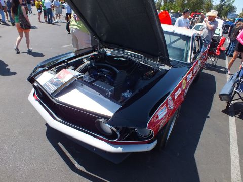 Black and white fastback coupe with open hood and red lettering at an outdoor car show