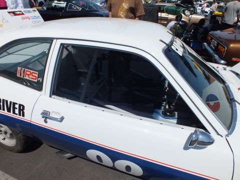 Close-up of a white race hatchback showing roll cage, RS badge and Driver door lettering