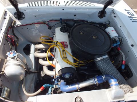 Close-up of a four-cylinder race engine with exhaust headers, air cleaner and yellow plug wires