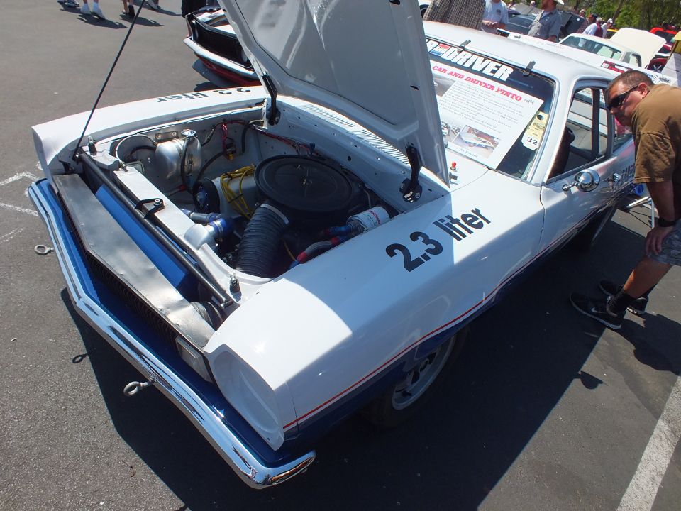 Rear three-quarter of a white race hatchback with open hood and 2.3 liter lettering