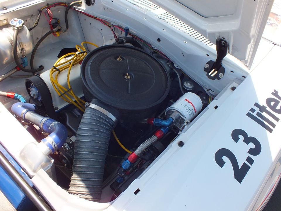 Engine bay close-up with black air cleaner, yellow plug wires and 2.3 liter fender lettering