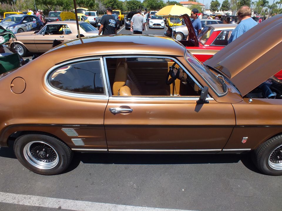 Brown two-door fastback coupe in profile with tan interior at an outdoor car show