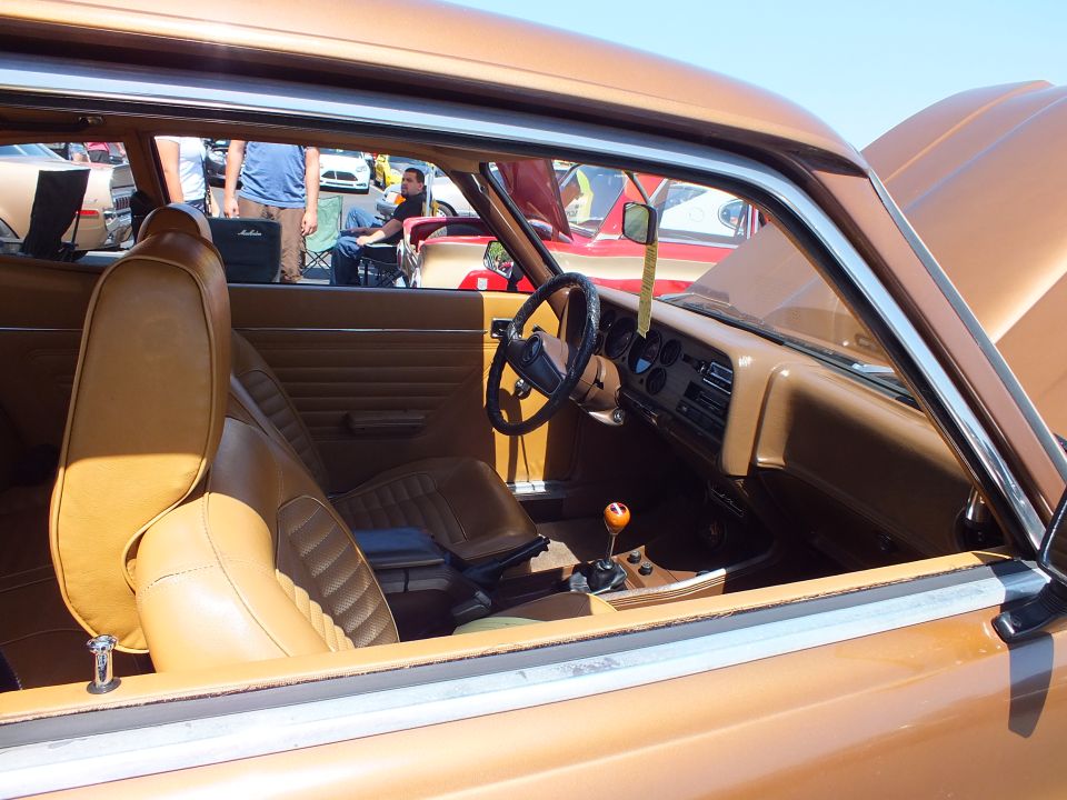 Tan leather interior of a coupe showing bucket seats, steering wheel and wood-knob shifter