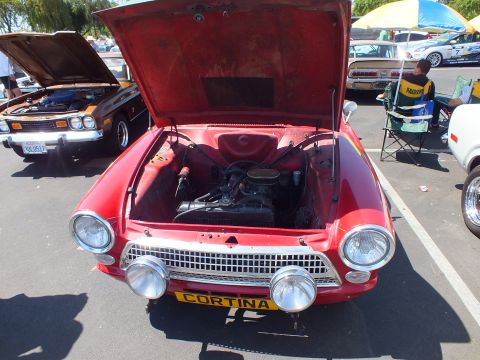 Front of a red Cortina with open hood, dual headlights and CORTINA front plate