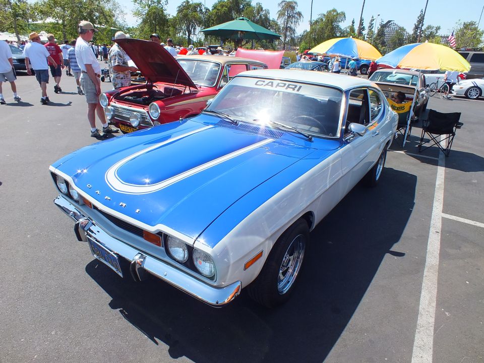 Blue and white Capri fastback with hood stripe and CAPRI lettering at an outdoor car show