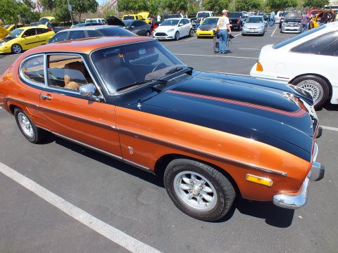 Copper and black two-tone fastback coupe in profile with alloy wheels at a car show