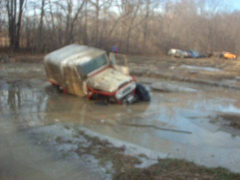1993 Ford Bronco - Multiple vehicles are stuck in the mud in a wooded area.