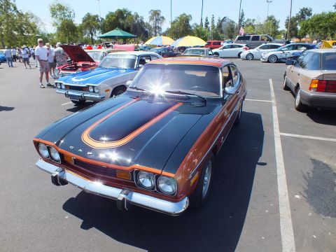 Brown and black Capri fastback with hood stripe and round headlights at a car show