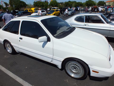 White three-door hatchback with sunroof and mesh alloy wheels at an outdoor car show