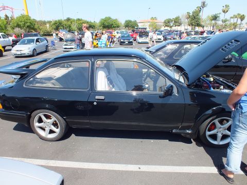 Black two-door hatchback with open hood, side view at car show