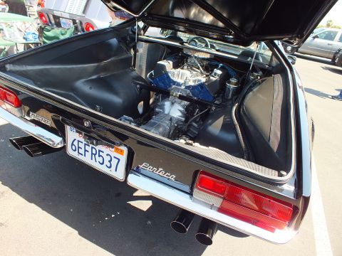 Black mid-engine sports car rear with open engine bay, dual exhaust, CA plate 6EFR537