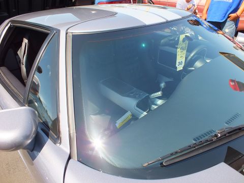Close view through windshield of silver sports car interior with show entry tag