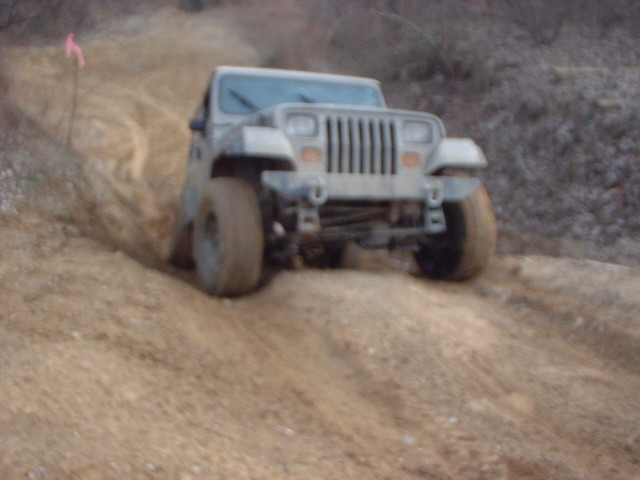 Gray Jeep Wrangler driving on a dirt hill, front view