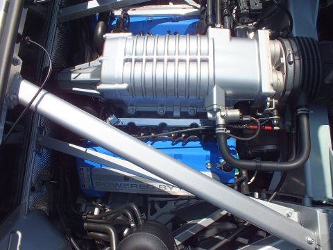 Close-up of finned supercharger atop blue V8 with POWERED BY text