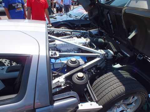 Silver Ford GT rear engine bay open at car show with crowd in background