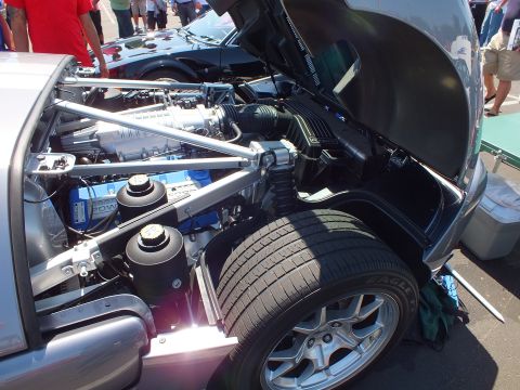 Silver Ford GT engine bay and rear tire with raised lid at sunny car show