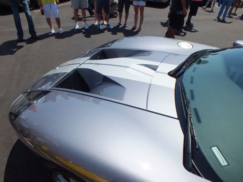 Rear deck and vented engine cover of silver Ford GT at crowded car show