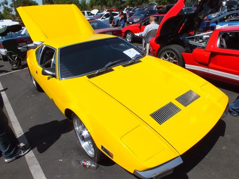 Yellow mid-engine wedge sports coupe with open rear hatch at outdoor car show