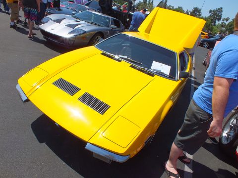 Yellow wedge sports car with raised hatch beside a silver Ford GT