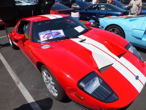 Red Ford GT with white stripes and brochure on windshield at a car show