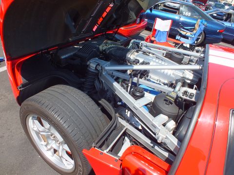 Open rear engine bay of a red supercar showing a supercharged V8