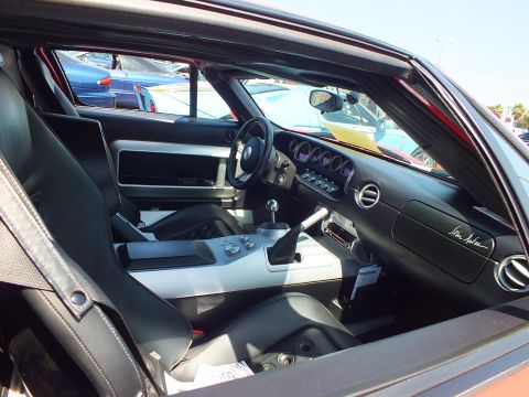 Interior of a dark sports car with manual shifter and signed dashboard