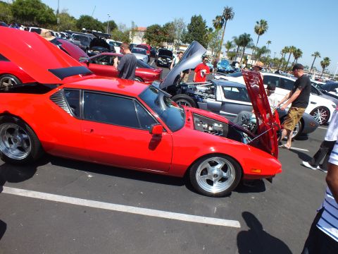 Red wedge sports coupe with raised door at a crowded car show