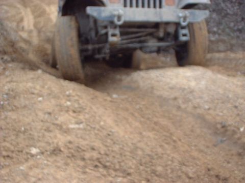 1993 Ford Bronco - The front of an off-road vehicle navigates a dirt path, kicking up dust.
