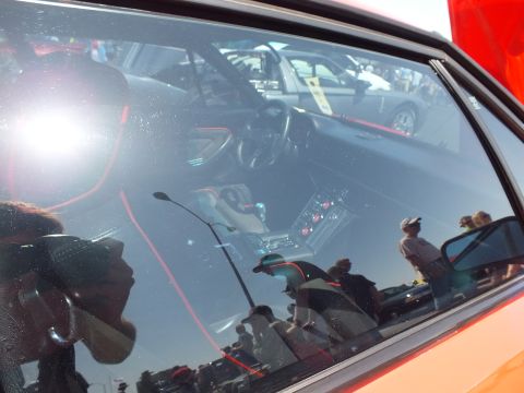 View through side window of a red sports car interior with red-stitched black seats