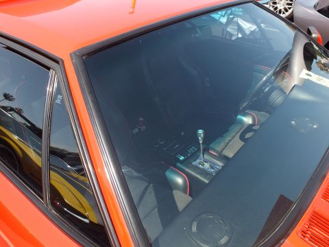 Interior of an orange car seen through windshield with shifter and bucket seats