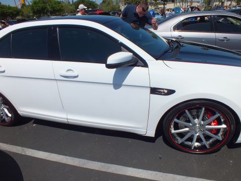 Side profile of a white sedan with chrome multi-spoke wheels and red calipers