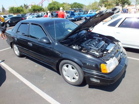 Black Ford Taurus SHO sedan with hood raised at outdoor car show