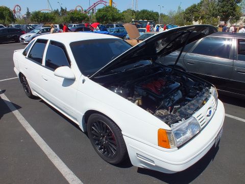 White Ford Taurus SHO sedan front quarter with hood up showing engine